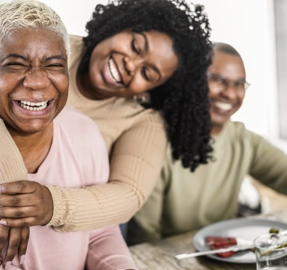 Happy black family eating lunch together at home - Main focus on mother face